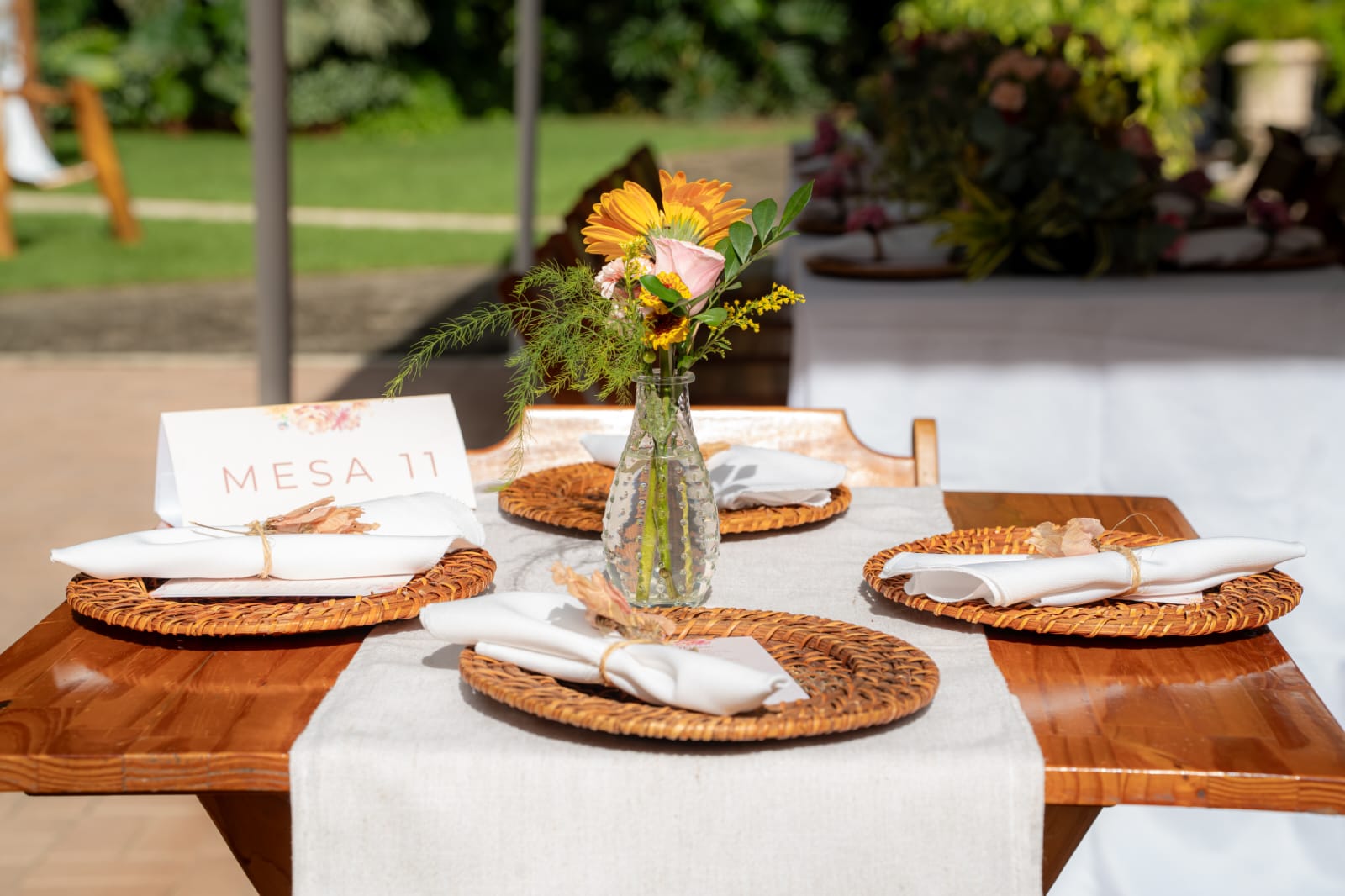 Mesa posta com sousplat de palha e arranjo de flores